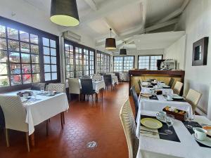 a restaurant with white tables and chairs and windows at Atlantis Hôtel in Mimizan