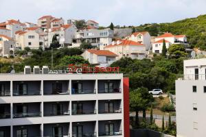 Un bâtiment blanc avec un panneau rouge en haut dans l'établissement D-Elegant Lapad Dubrovnik, à Dubrovnik