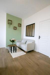 ein Wohnzimmer mit einem weißen Sofa und einem Tisch in der Unterkunft Appartement - Centre ville de Cambrai in Cambrai