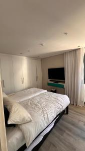 a bedroom with a large bed and a flat screen tv at dockrail and cast anchor drive Apartment in Cape Town
