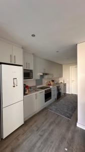 una cocina vacía con armarios blancos y nevera en dockrail and cast anchor drive Apartment, en Ciudad del Cabo