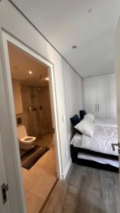 um quarto com uma cama e uma casa de banho com um WC em dockrail and cast anchor drive Apartment em Cidade do Cabo