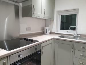 a kitchen with white cabinets and a sink at Ty Twt in Wrexham