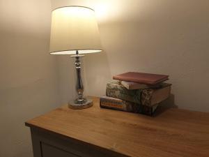 a lamp sitting on a table next to three books at Ty Twt in Wrexham