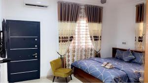 a bedroom with a blue bed and a yellow chair at Ayan Villas in Accra