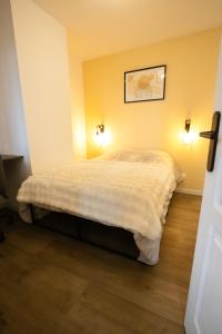 a bed in a room with two lights on the wall at Appartement - Centre ville de Cambrai in Cambrai