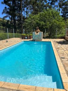 een blauw zwembad met een persoon in een stoel ernaast bij Hospedagem Florenza in Aiuruoca
