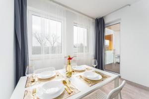 a white dining room with a white table and chairs at Apartament Miodowy Dom Kołobrzeg in Kołobrzeg