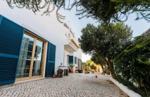 a house with blue doors and a stone driveway at Aldeia Caiçara Surf House in Sagres