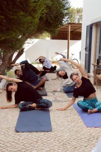 a group of people doing yoga on the ground at Aldeia Caiçara Surf House in Sagres