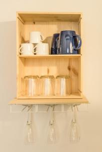 a wooden shelf with glasses and cups on it at Biciclò Mini Studio in Ferrara