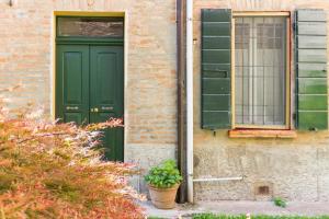 a green door and window on a brick building at Biciclò Mini Studio in Ferrara