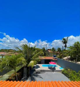 uma vista para uma piscina com um guarda-sol e palmeiras em Casa de praia Amarópolis em Paripueira
