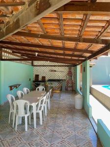 a dining room with a table and white chairs at Casa de praia Amarópolis in Paripueira