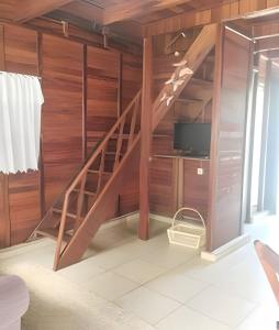 a living room with a wooden staircase with a tv at Chalés Caraguá Massaguaçu in Caraguatatuba