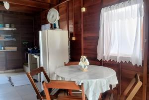 a kitchen with a table and chairs and a refrigerator at Chalés Caraguá Massaguaçu in Caraguatatuba