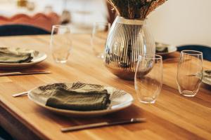 einem Holztisch mit Tellern, Gläsern und einer Vase in der Unterkunft Cosy Haven SGDB in Sainte-Geneviève-des-Bois