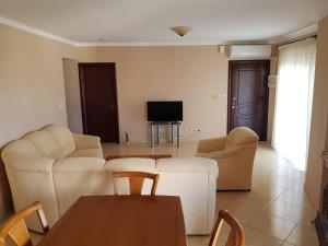 a living room with white furniture and a television at Kriopigi Apartments 2 in Kriopigi