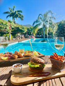 un tavolo con un panino e bicchieri da vino accanto a una piscina di Tropicana Suites a Deshaies