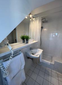 ein weißes Badezimmer mit einem Waschbecken und einer Badewanne in der Unterkunft Hotel Pelikan in Kitzingen