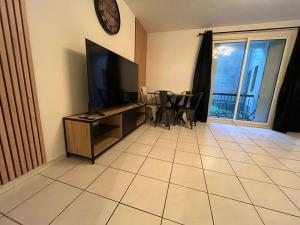 a living room with a television and a table and chairs at Spacieux appartement ~ Halles ~ Wifi ~ Centre in Narbonne