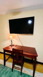 een houten bureau met een lamp en een televisie aan een muur bij Lake Arenal Brewery & Hotel in Tilarán