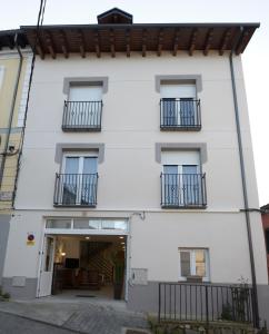 a white building with balconies and a doorway at Hostel El Campano in Villafranca del Bierzo