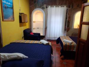 Habitación con 2 camas, silla y ventana en hotel posada Gutierrez antigua, en Antigua Guatemala