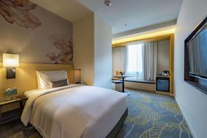 um quarto de hotel com uma cama e uma grande janela em Hilton Garden Inn Kuala Lumpur - North em Kuala Lumpur