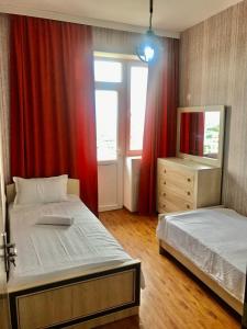 a bedroom with two beds and a window with red curtains at Best choice in Kutaisi