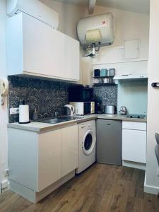 eine Küche mit weißen Schränken und einer Waschmaschine in der Unterkunft Appartement Le Tivoli proche du centre in Albi