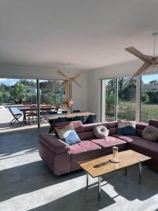 een woonkamer met een paarse bank en een tafel bij Magnifique maison proche lac avec piscine chauffée in Sanguinet