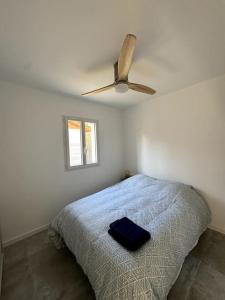 een slaapkamer met een bed en een plafondventilator bij Magnifique maison proche lac avec piscine chauffée in Sanguinet