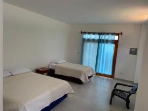 een kamer met 2 bedden en een raam bij Penguin House in Puerto Villamil