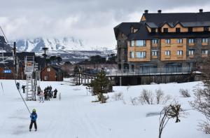 a group of people skiing in the snow in front of a building at Grand Hotel Caviahue in Caviahue