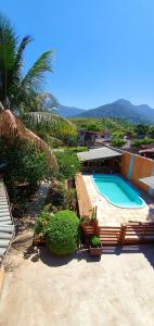 a swimming pool with a palm tree and a building at Suítes no paraíso da Ilhabela in Ilhabela