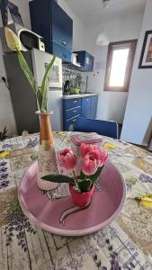 a table with a pink plate with a vase and flowers at Pambi House in Quartu SantʼElena