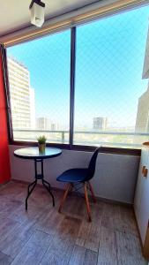 einen Tisch und einen Stuhl in einem Zimmer mit einem großen Fenster in der Unterkunft Smart Home Barrio Italia in Santiago