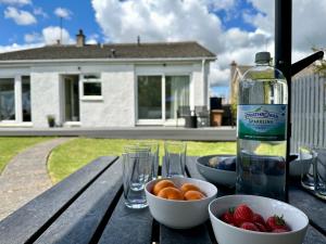 a bottle of water and bowls of fruit on a wooden table at Lovely house & garden, short walk to town & beach. in Fife