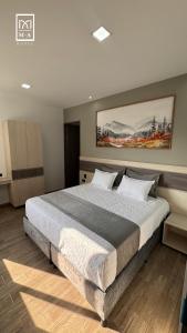 een slaapkamer met een groot bed en een schilderij aan de muur bij M A Hotel in Popayan