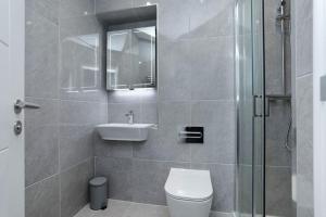 a bathroom with a toilet and a sink and a shower at SoHot Stays Beach Haven Apt With Sea Views A Balcony & Free Parking in Ramsgate +45 photos