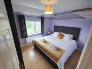 a purple bedroom with a bed with towels on it at Peaceful 3 Bedroom House wFree Parking Nature in Falmer