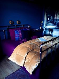 Un dormitorio con una cama con una manta. en L'ancien Mystic ManOir DeDame, en Ventron