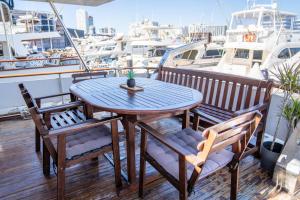a wooden table and chairs on a deck with boats at Boat ALOHA in Barcelona