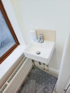 La salle de bains est pourvue d'un lavabo blanc et d'une fenêtre. dans l'établissement SwankyHome4Groups/Contractors/M5, à Dudley
