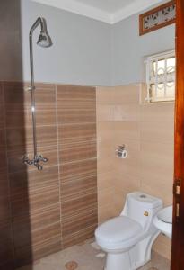 a bathroom with a toilet and a shower at Migingo Suites in Entebbe