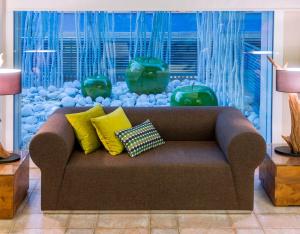 un sofá con almohadas en la sala de estar con un acuario en Hotel Kaktus Playa - Adults Recommended, en Calella