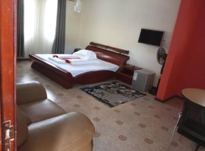 a bedroom with a bed and a couch and a television at Migingo Suites in Entebbe