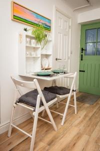 einen Tisch und Stühle in einem Zimmer mit grüner Tür in der Unterkunft Cwtch Lackerlee in Haverfordwest
