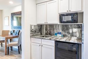 a kitchen with white cabinets and a microwave and a table at Luau I 7605 Studio in Destin